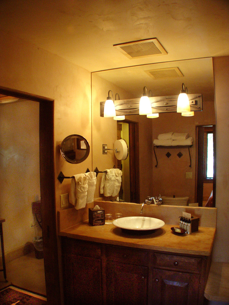 Immagine di un bagno di servizio stile americano di medie dimensioni con ante con bugna sagomata, ante in legno bruno, WC a due pezzi, pareti beige, pavimento in terracotta, lavabo a bacinella, top in cemento e pavimento rosso