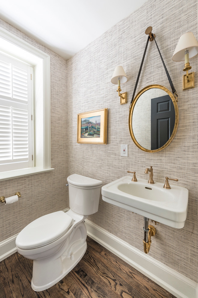 Inredning av ett klassiskt mellanstort toalett, med en toalettstol med separat cisternkåpa, mörkt trägolv, beige väggar, ett piedestal handfat och brunt golv