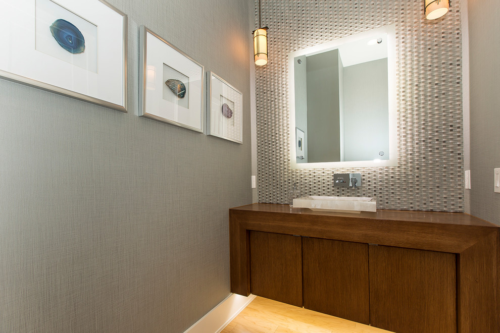 This is an example of a small contemporary cloakroom in Dallas with freestanding cabinets, brown cabinets, grey tiles, ceramic tiles, grey walls, light hardwood flooring, a vessel sink, wooden worktops, brown floors and brown worktops.
