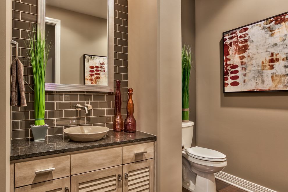 Medium sized traditional cloakroom in Omaha with louvered cabinets, light wood cabinets, a two-piece toilet, brown walls, medium hardwood flooring, a vessel sink, brown tiles, metro tiles, granite worktops and brown floors.