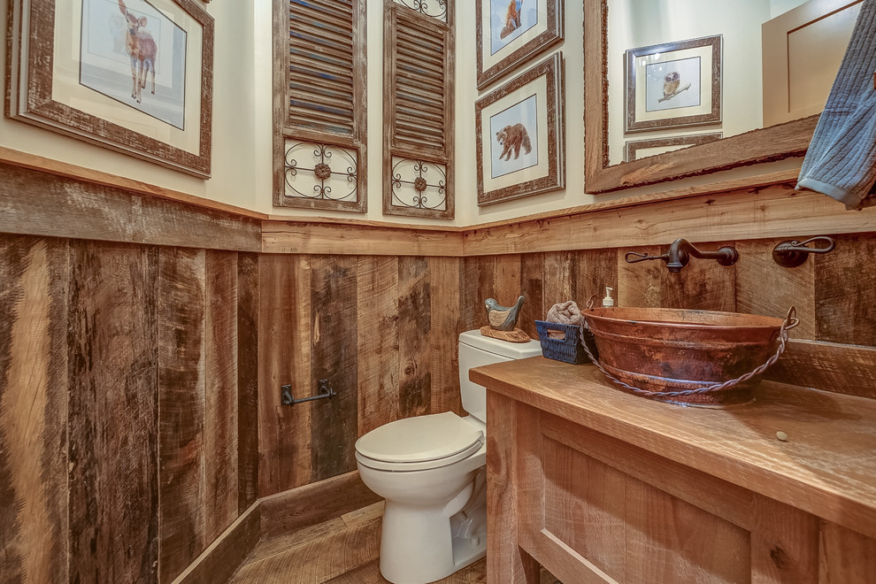 Example of a mountain style medium tone wood floor powder room design in Atlanta with light wood cabinets, a two-piece toilet, beige walls, a vessel sink, wood countertops and brown countertops