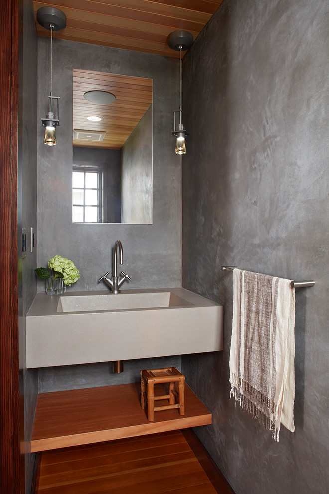 Cette photo montre un WC et toilettes tendance avec un mur gris, un sol en bois brun, un lavabo intégré et un sol marron.