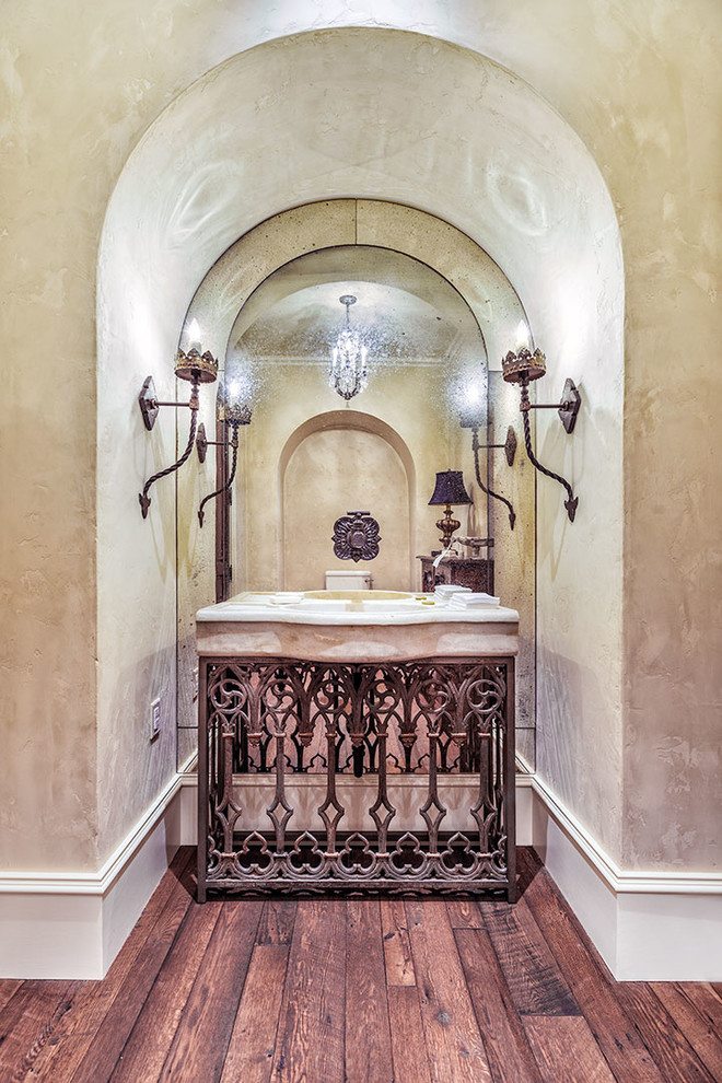 Ejemplo de aseo mediterráneo grande con paredes beige, suelo de madera oscura, lavabo integrado y encimera de mármol