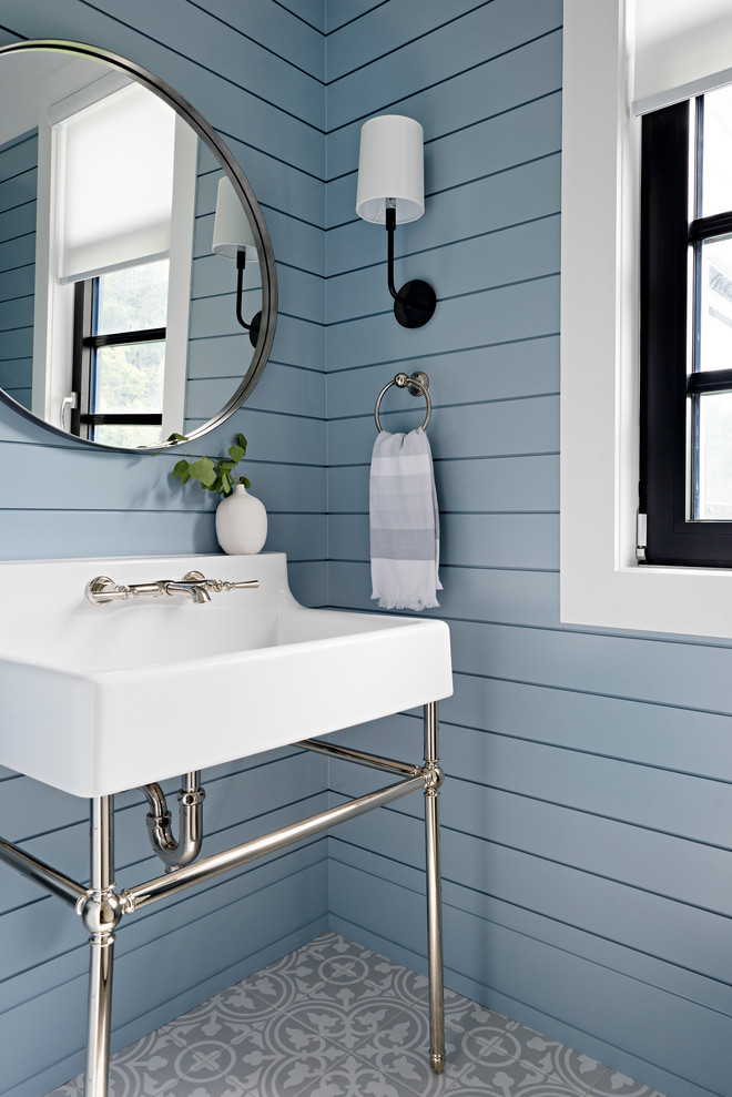 Diseño de aseo tradicional renovado con paredes azules, lavabo tipo consola, suelo multicolor y machihembrado