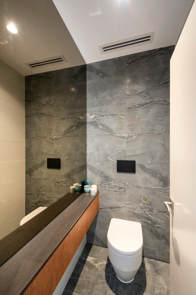 Esempio di un piccolo bagno di servizio contemporaneo con ante lisce, WC sospeso, piastrelle in pietra, pavimento in pietra calcarea e mobile bagno sospeso