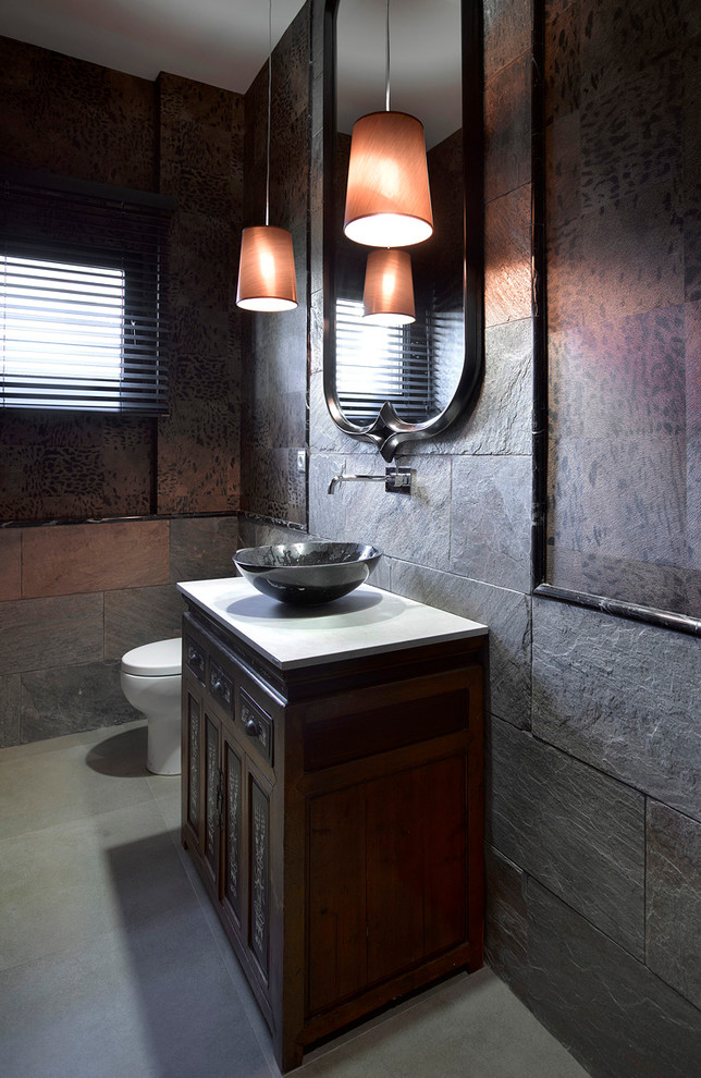 Idee per un piccolo bagno di servizio etnico con consolle stile comò, ante in legno bruno, WC a due pezzi e lavabo a bacinella