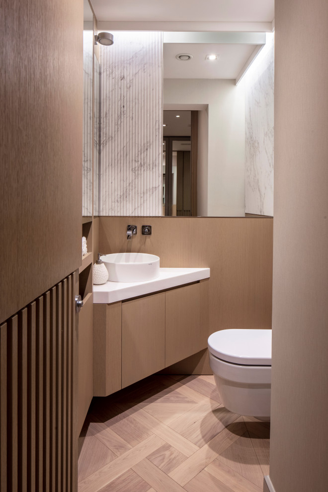 Esempio di un bagno di servizio minimal con ante lisce, ante in legno chiaro, parquet chiaro, lavabo a bacinella, pavimento beige, top bianco e mobile bagno sospeso