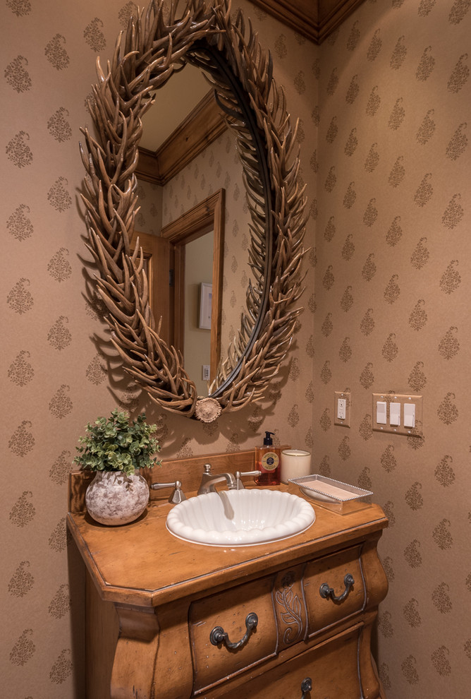 Immagine di un bagno di servizio rustico di medie dimensioni con consolle stile comò, ante in legno bruno, pareti multicolore, lavabo da incasso e top in legno