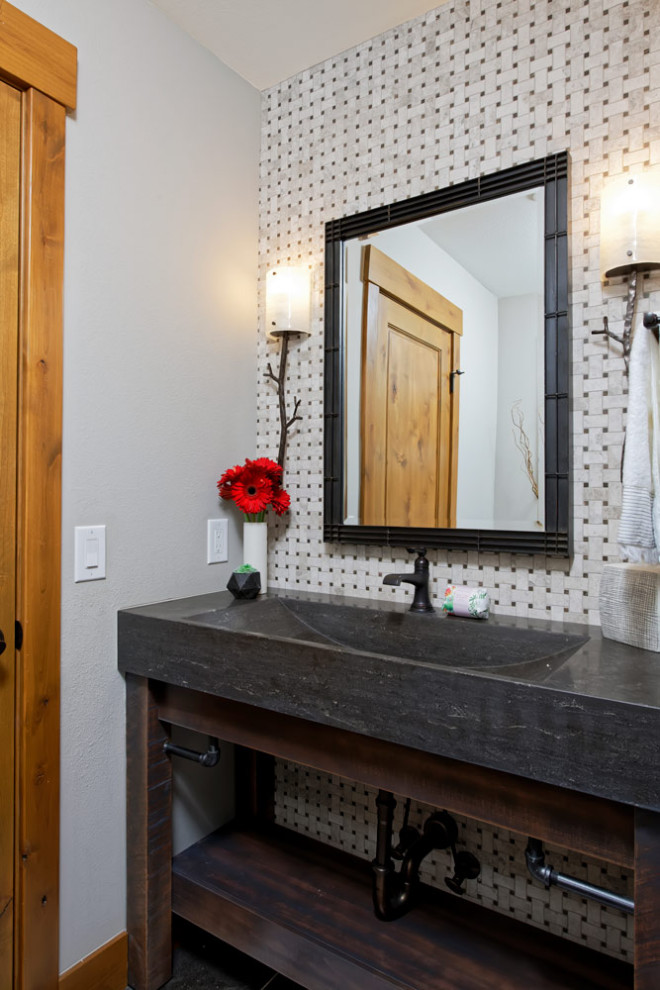 デンバーにある高級な中くらいなラスティックスタイルのおしゃれなトイレ・洗面所 (オープンシェルフ、オーバーカウンターシンク、黒い洗面カウンター、造り付け洗面台) の写真