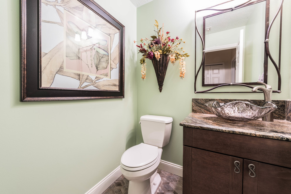 Réalisation d'un petit WC et toilettes tradition en bois foncé avec un placard à porte plane, un mur vert, un sol en carrelage de porcelaine, une vasque, un plan de toilette en granite et un sol multicolore.