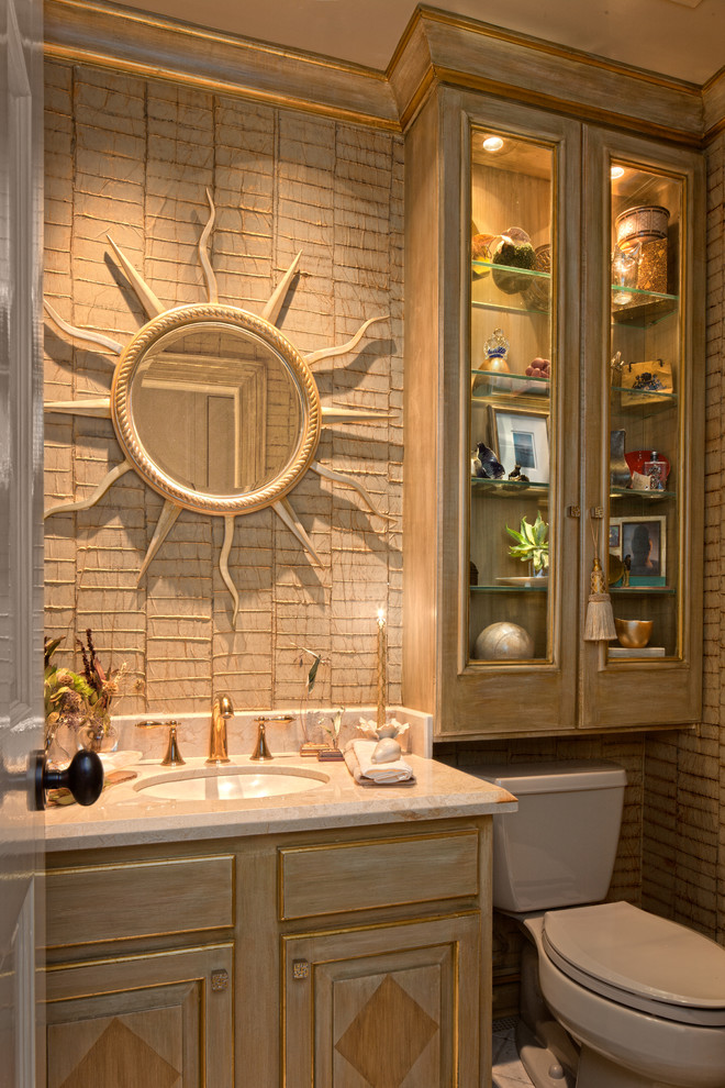 ニューオリンズにある小さなおしゃれなトイレ・洗面所 (アンダーカウンター洗面器、レイズドパネル扉のキャビネット、大理石の洗面台、分離型トイレ、ベージュの壁) の写真