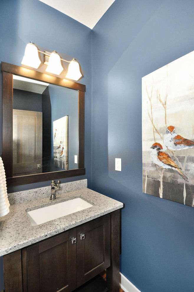 Cette image montre un WC et toilettes traditionnel en bois foncé avec un mur bleu, un lavabo encastré et un placard à porte shaker.