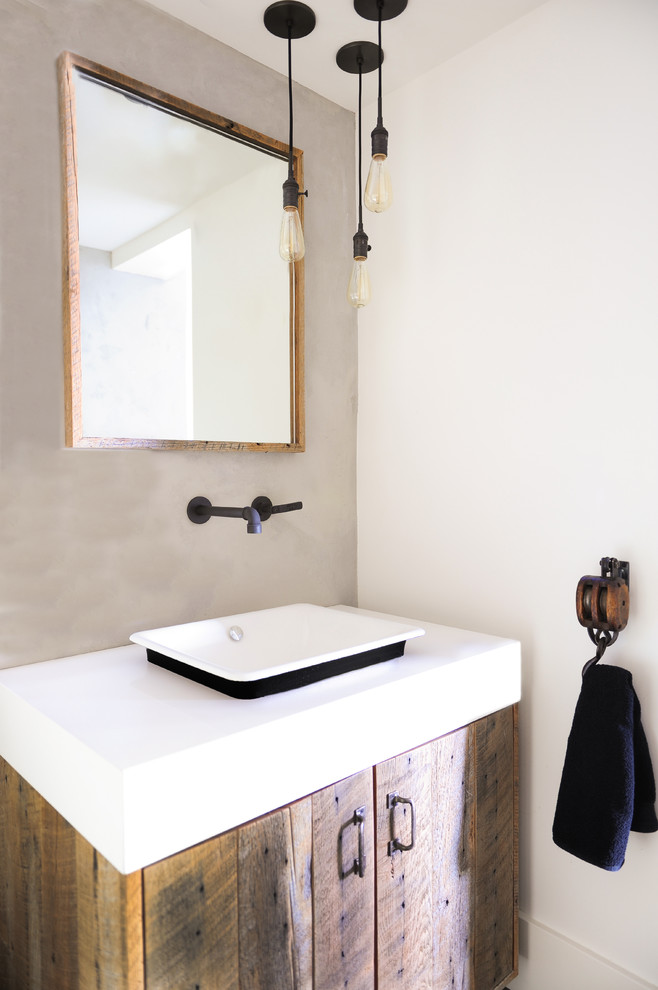 Inredning av ett industriellt mellanstort vit vitt toalett, med släta luckor, bruna skåp, brun kakel, vita väggar, mörkt trägolv, brunt golv, ett fristående handfat och bänkskiva i kvarts