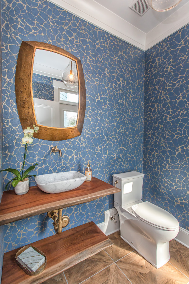 На фото: туалет в стиле неоклассика (современная классика) с открытыми фасадами, унитазом-моноблоком, синими стенами, светлым паркетным полом, столешницей из дерева, бежевым полом и коричневой столешницей