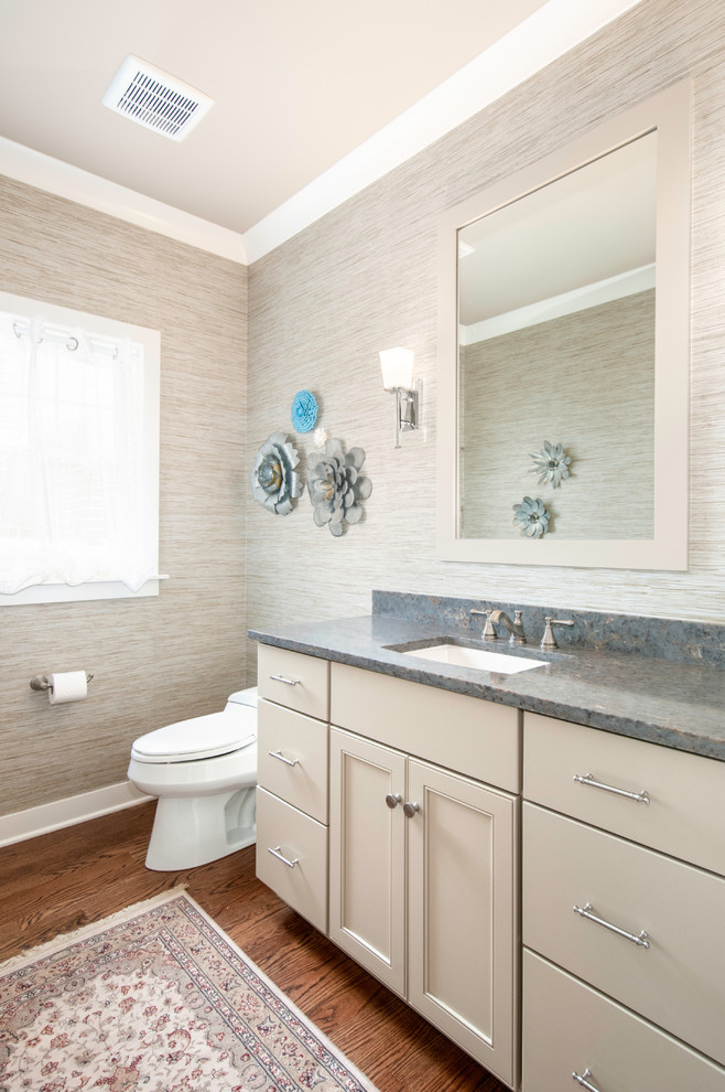 This is an example of a small classic cloakroom in Chicago with beige cabinets, a one-piece toilet, beige walls, medium hardwood flooring, a submerged sink, engineered stone worktops, grey worktops, recessed-panel cabinets and brown floors.