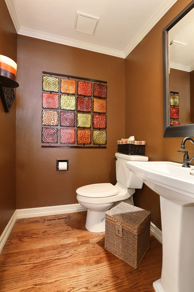 Mittelgroße Klassische Gästetoilette mit Wandtoilette mit Spülkasten, brauner Wandfarbe, braunem Holzboden, Sockelwaschbecken und Mineralwerkstoff-Waschtisch in Denver