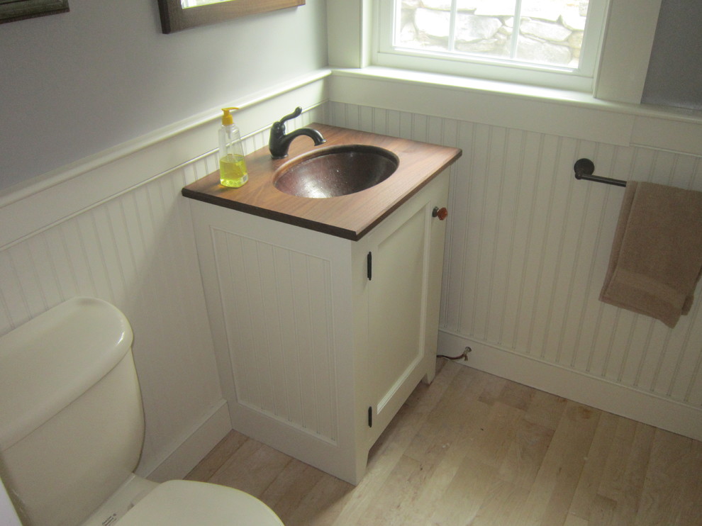 Réalisation d'un petit WC et toilettes champêtre avec un lavabo encastré, des portes de placard blanches, un plan de toilette en bois et un placard avec porte à panneau encastré.