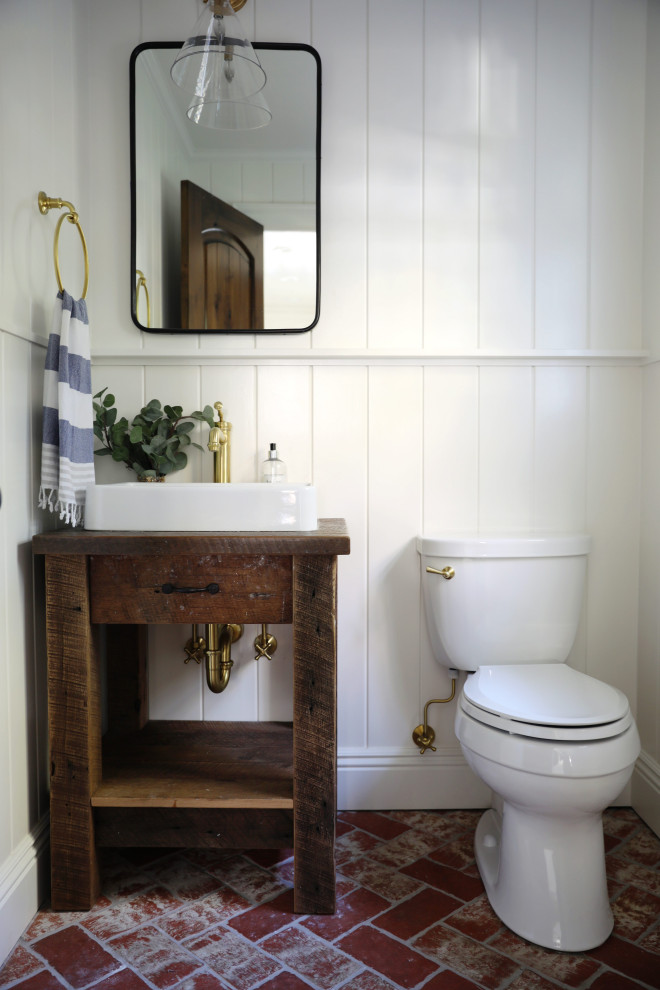 Small country cloakroom in New York with brown cabinets, white walls, brick flooring, a vessel sink, wooden worktops, red floors, brown worktops, a freestanding vanity unit and panelled walls.