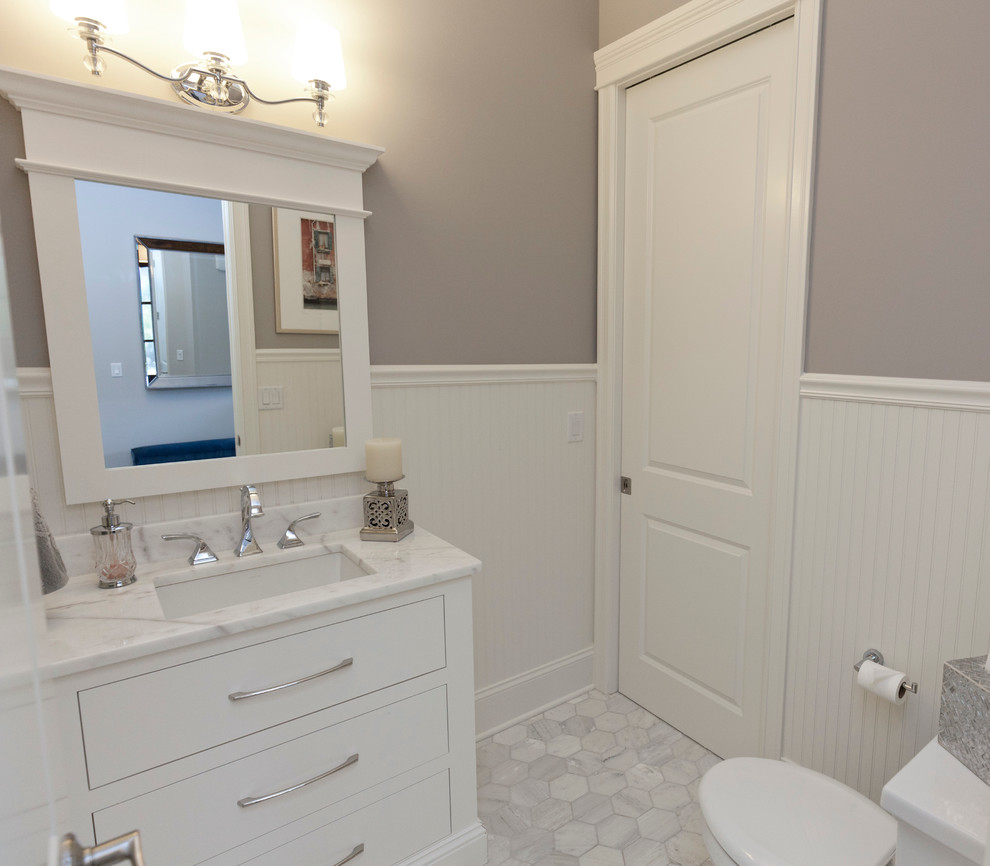 This is an example of a small country cloakroom in Chicago with a submerged sink, flat-panel cabinets, white cabinets, marble worktops, a two-piece toilet, grey tiles, white tiles, grey walls and marble flooring.