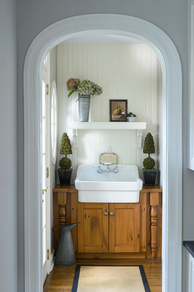 Inspiration for a small country powder room remodel in New York with recessed-panel cabinets, medium tone wood cabinets, wood countertops, white walls and brown countertops