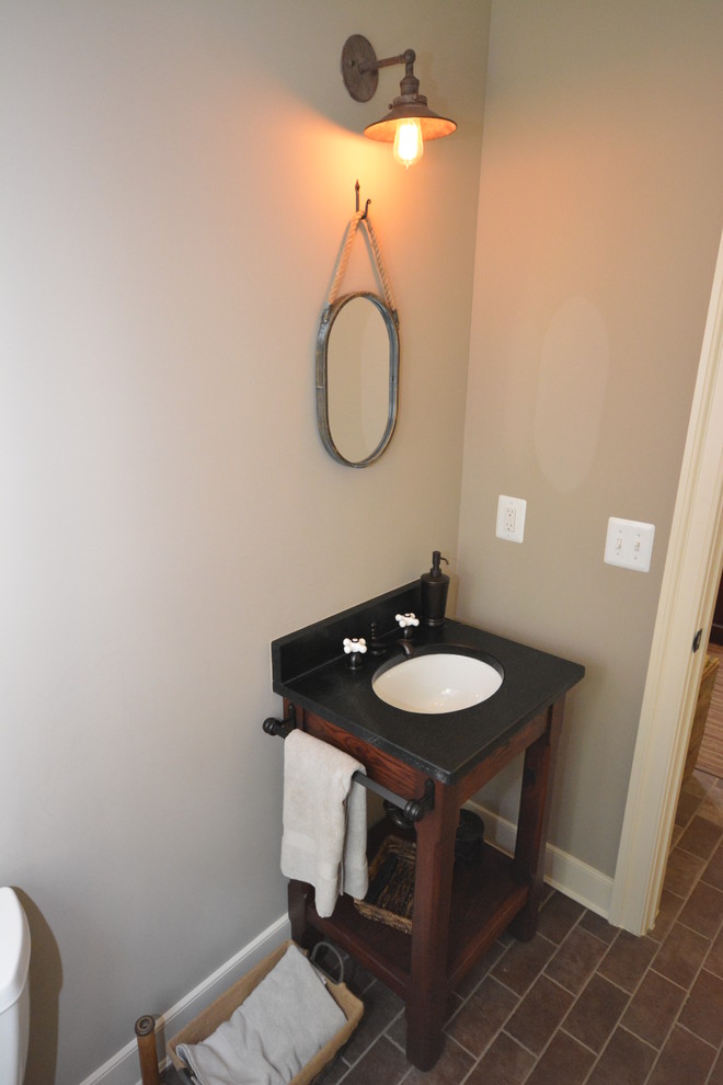 Aménagement d'un petit WC et toilettes campagne en bois foncé avec un lavabo encastré, un plan de toilette en stéatite, WC à poser, un carrelage marron et un mur beige.