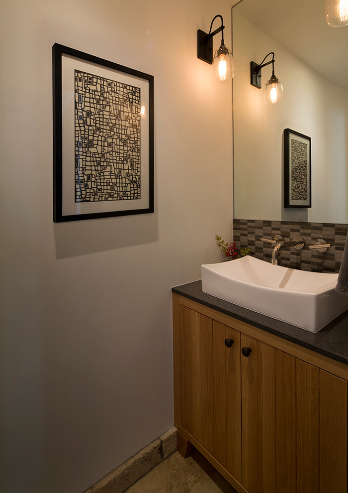 Cette image montre un petit WC et toilettes rustique en bois brun avec une vasque, un placard à porte plane, un carrelage gris, un carrelage de pierre, un mur blanc et un sol en travertin.