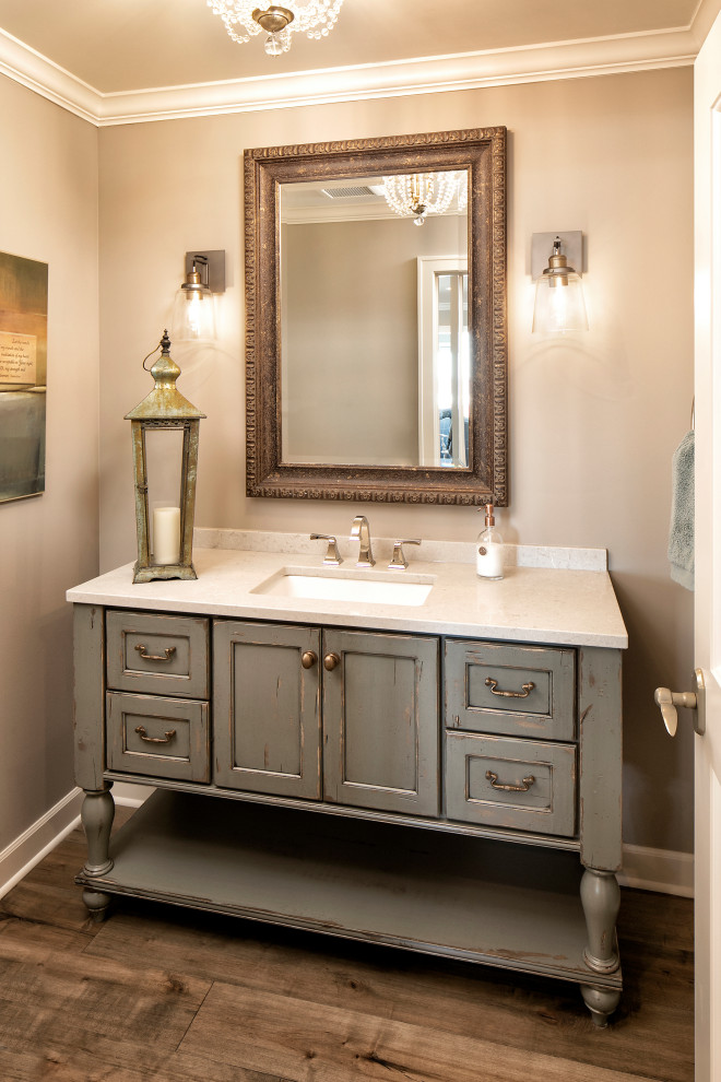 Inspiration for a mid-sized country medium tone wood floor and brown floor powder room remodel in Minneapolis with recessed-panel cabinets, green cabinets, beige walls, an undermount sink, white countertops and granite countertops