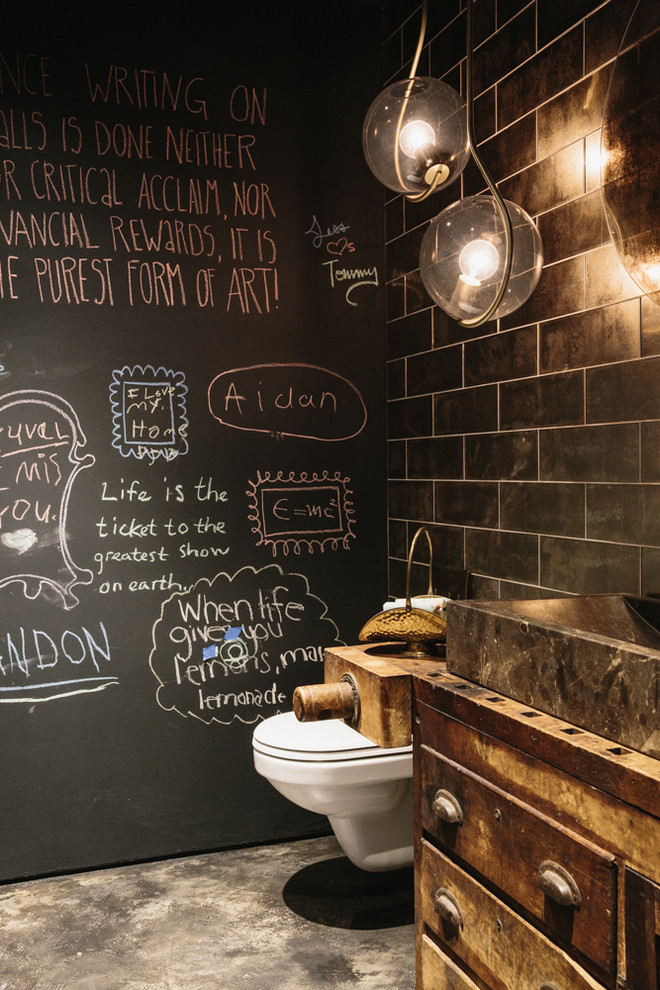 Inspiration for an industrial black tile concrete floor and gray floor powder room remodel in New York with furniture-like cabinets, distressed cabinets, black walls and a vessel sink