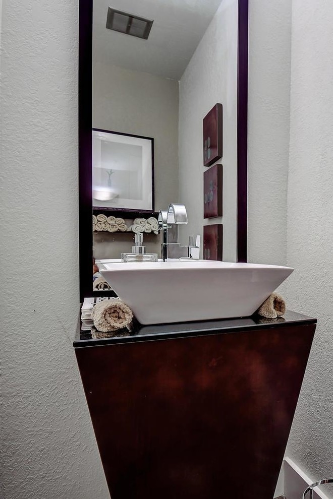 Cette image montre un petit WC et toilettes minimaliste en bois foncé avec un plan de toilette noir, un mur blanc et parquet foncé.