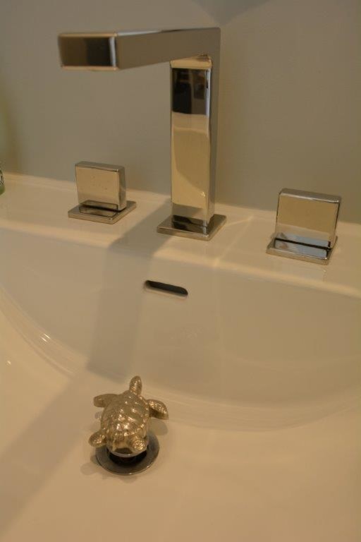 Inredning av ett maritimt litet toalett, med möbel-liknande, grå skåp, en toalettstol med hel cisternkåpa, grå väggar och ett integrerad handfat