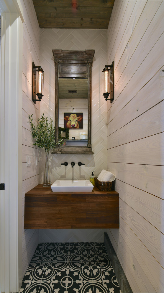 Foto på ett lantligt brun toalett, med beige kakel, kakelplattor, beige väggar, cementgolv, ett fristående handfat, träbänkskiva och flerfärgat golv