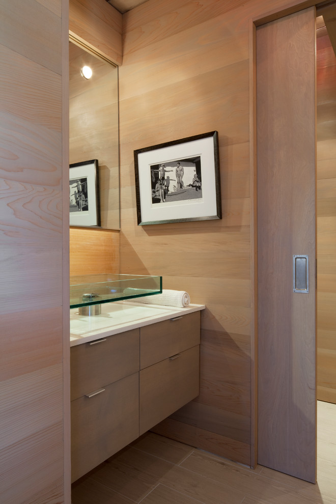 Cette image montre un petit WC et toilettes design en bois clair avec une vasque, un placard à porte plane, un mur beige, parquet clair, un plan de toilette en quartz modifié et un sol beige.
