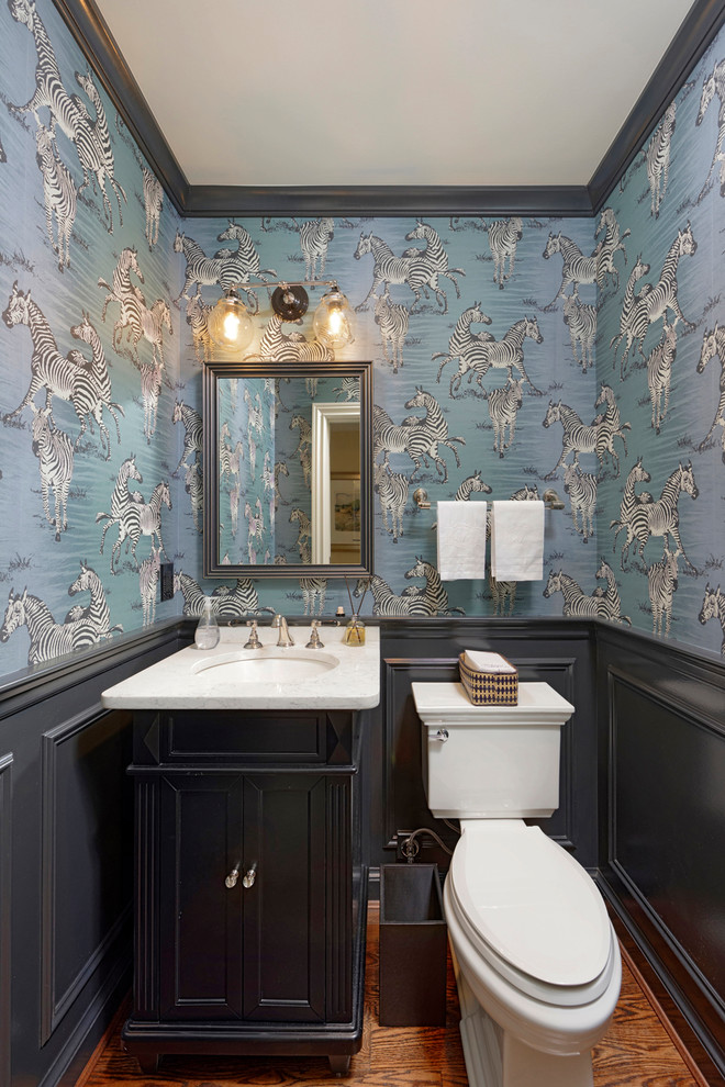 Inspiration for a traditional cloakroom in DC Metro with freestanding cabinets, black cabinets, a two-piece toilet, blue walls, medium hardwood flooring, a submerged sink, brown floors and white worktops.