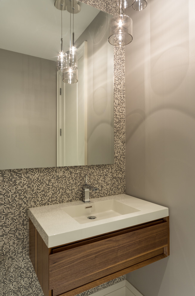 Exempel på ett litet modernt toalett, med ett integrerad handfat, släta luckor, skåp i mellenmörkt trä, bänkskiva i akrylsten, flerfärgad kakel, mosaik och grå väggar