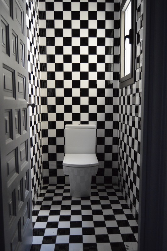 Réalisation d'un petit WC et toilettes bohème avec WC à poser, un carrelage noir et blanc, des carreaux de céramique, un mur multicolore, un sol en carrelage de céramique et un sol multicolore.