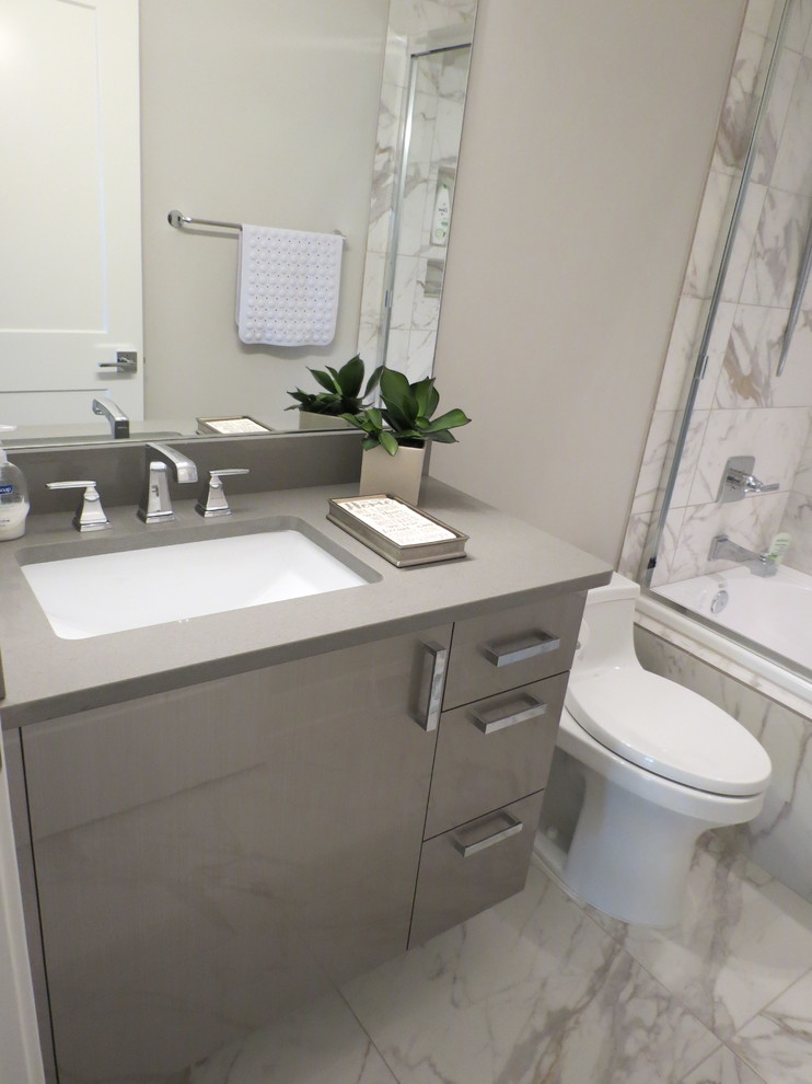 Idée de décoration pour un petit WC et toilettes design avec un placard à porte plane, des portes de placard grises, WC à poser, un mur gris, un sol en marbre, un lavabo encastré, un plan de toilette en quartz modifié et un sol blanc.