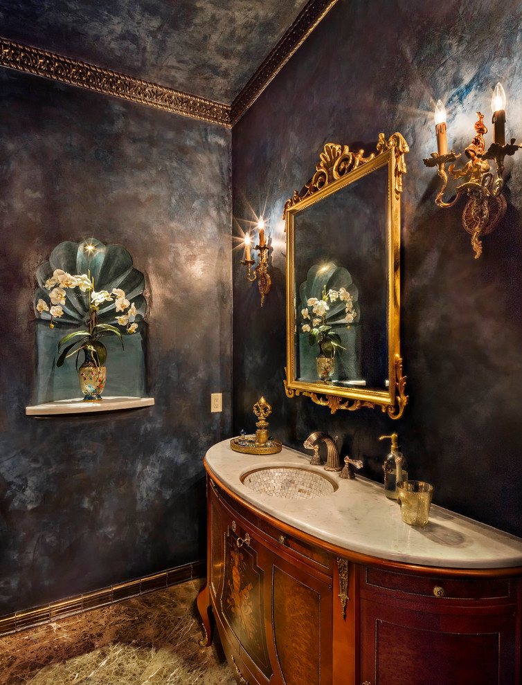 Réalisation d'un WC et toilettes méditerranéen en bois brun de taille moyenne avec un placard en trompe-l'oeil, WC à poser, un carrelage beige, un carrelage de pierre, un mur violet, un sol en marbre et un lavabo encastré.