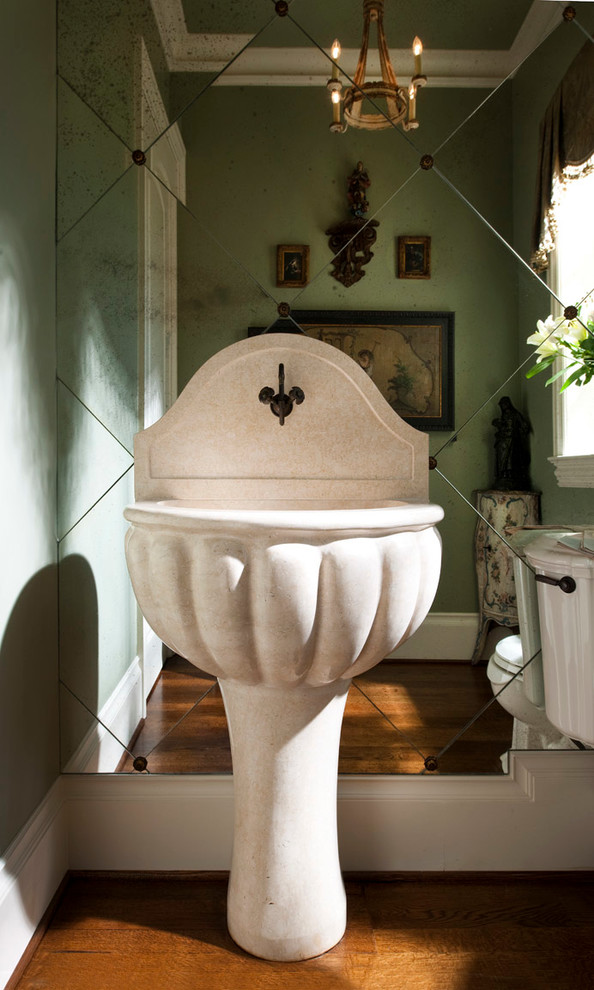 Inspiration for a mid-sized timeless medium tone wood floor powder room remodel in Dallas with a pedestal sink, a two-piece toilet and green walls