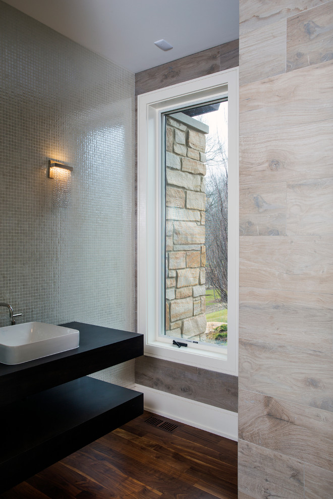 Large traditional cloakroom in Chicago with black cabinets, a wall mounted toilet, grey tiles, ceramic tiles, grey walls, medium hardwood flooring, a built-in sink, wooden worktops and open cabinets.