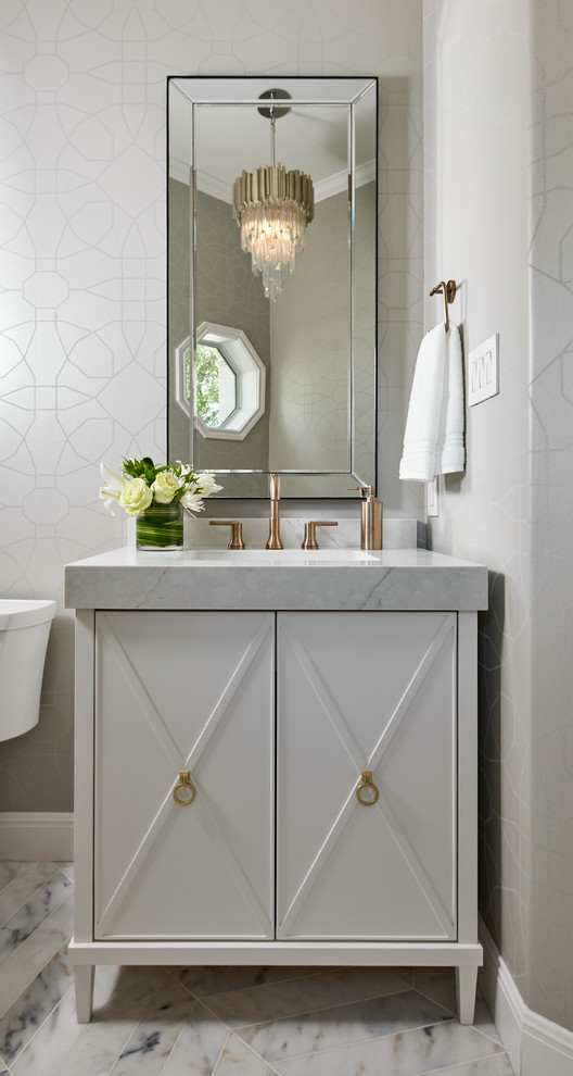 Inredning av ett klassiskt litet grå grått toalett, med möbel-liknande, vita skåp, grå väggar, marmorgolv, ett undermonterad handfat, bänkskiva i kvarts, grått golv, en toalettstol med separat cisternkåpa och grå kakel