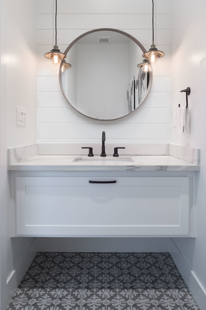Cette image montre un WC et toilettes rustique de taille moyenne avec un placard à porte shaker, des portes de placard blanches, un carrelage blanc, un mur blanc, carreaux de ciment au sol, un lavabo encastré, un plan de toilette en marbre, un sol gris et un plan de toilette gris.