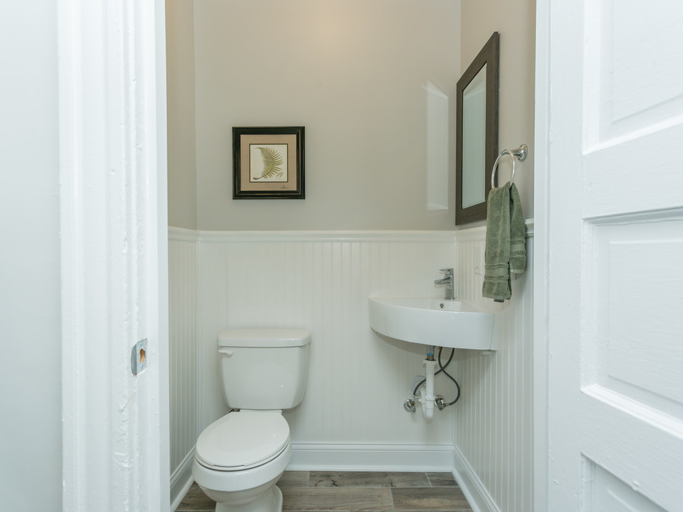 Example of a small classic ceramic tile and brown floor powder room design in St Louis with gray walls, a wall-mount sink and a two-piece toilet
