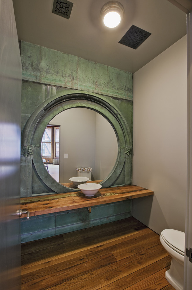 Foto på ett mellanstort industriellt brun toalett, med ett fristående handfat, träbänkskiva, gröna väggar, mellanmörkt trägolv och brunt golv