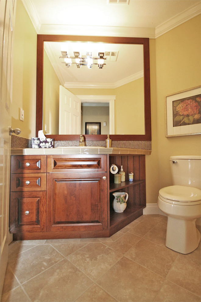 Réalisation d'un petit WC et toilettes tradition en bois brun avec un lavabo posé, un placard avec porte à panneau surélevé, un plan de toilette en carrelage, WC séparés, un carrelage marron, des carreaux de céramique, un mur beige et un sol en carrelage de céramique.