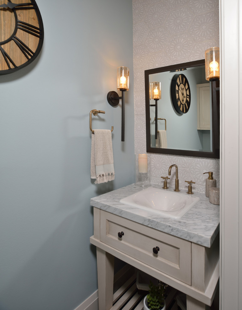Idée de décoration pour un WC et toilettes champêtre de taille moyenne avec un placard sans porte, des portes de placard beiges, un mur bleu, un lavabo posé et un plan de toilette en marbre.