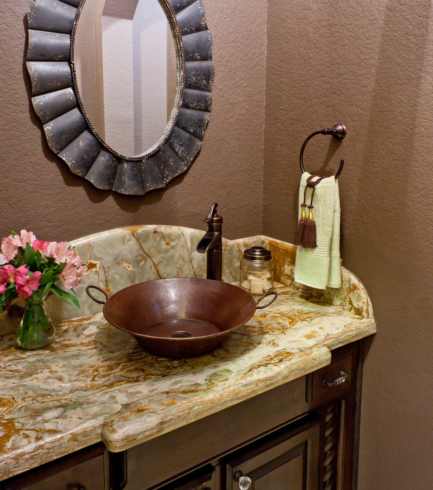 Small elegant powder room photo in Houston with a vessel sink, raised-panel cabinets, dark wood cabinets, marble countertops and brown walls