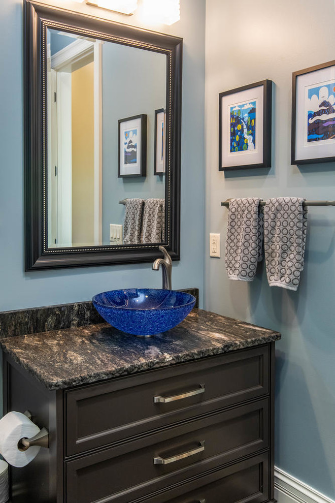 Small elegant dark wood floor and brown floor powder room photo in Other with recessed-panel cabinets, gray cabinets, a two-piece toilet, blue walls, a vessel sink, granite countertops and black countertops