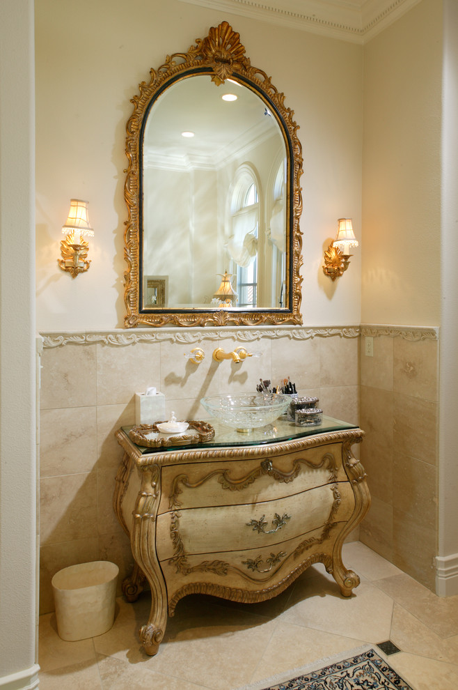 Inredning av ett klassiskt mycket stort toalett, med möbel-liknande, beige skåp, beige kakel, keramikplattor, beige väggar, travertin golv, ett fristående handfat och bänkskiva i glas