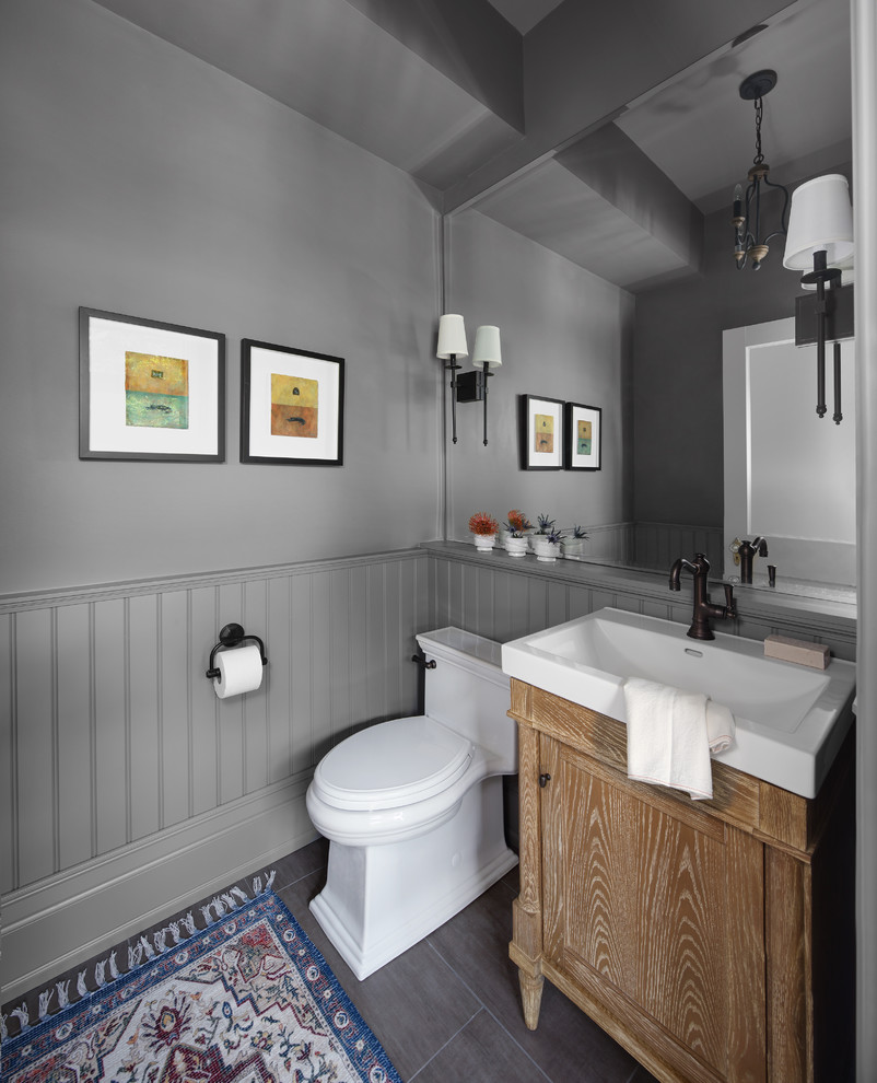 Idées déco pour un petit WC et toilettes en bois clair avec un placard avec porte à panneau encastré, un mur gris, un sol en carrelage de porcelaine, un lavabo intégré, un sol gris et un plan de toilette blanc.