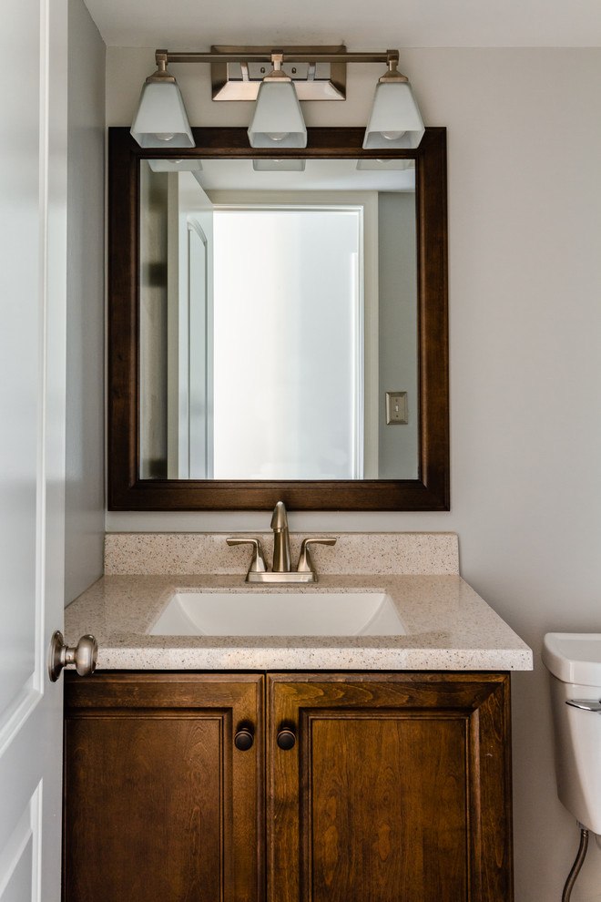 This is an example of a small classic cloakroom in Philadelphia with raised-panel cabinets, dark wood cabinets, grey walls, a submerged sink and beige worktops.